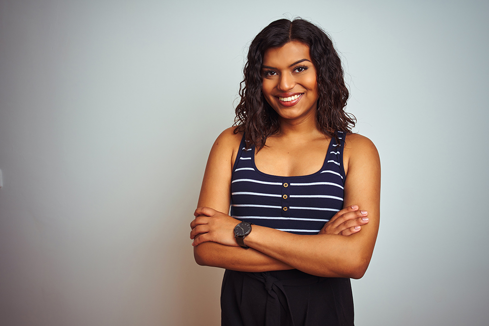 Transgender woman wearing striped t-shirt over isolated white background happy face smiling with crossed arms looking at the camera. Positive person.